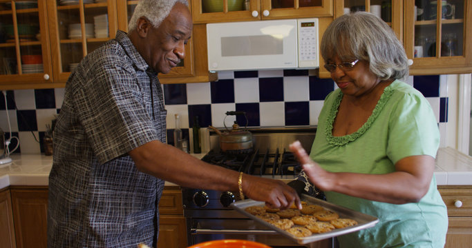 Mature black couple baking cookies after lunch