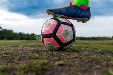 A young athlete puts their cleated food on a soccer ball.  Concepts: youth sports, athlete, focus, preparation, practice, intensity, aspiration, dreams