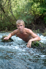 portrait of a young man among the wild stones on the rapid river