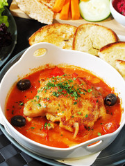 Chicken stewed with vegetables in tomato sauce on a white bowl