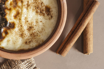 Baked rice pudding turkish milky dessert sutlac in earthenware casserole with cinnamon sticks