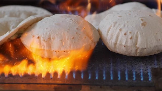 Slow motion footage of making of Phulka a kind of Chapati: Indian thin bread made from wheat dough being baked on gas