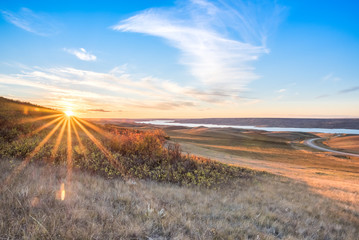 Sunset over autumn leaves on a hillside overlooking Lake Diefenbaker in the Saskatchewan Landing Provincial Park - obrazy, fototapety, plakaty