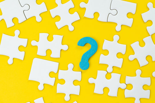 Business solution to solve problem, job search or career path metaphor or FAQs frequently asked question concept, blue question mark surround with white jigsaw puzzle on solid yellow background