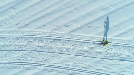 AERIAL, TOP DOWN: Flying above energetic woman skiing down the narrow trails on a sunny day. Cinematic shot of active female tourist cross country skiing during fun winter holiday in scenic Slovenia.