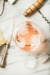 Obraz na płótnie Canvas Flat-lay of glass of rose wine with ice cubes, cheese and fresh figs over marble background. Summer wine and snack set, top view, close-up, selective focus