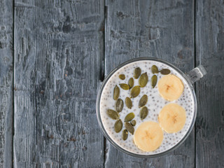 Chia seed pudding with banana and pumpkin seed on a dark wooden table. The view from the top. Flat lay.