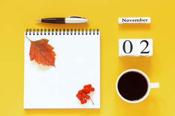 Autumn composition. Wooden calendar November 2 cup of coffee, empty open notepad with pen and yellow oak leaf on yellow background. Top view Flat lay Mockup Concept Hello November