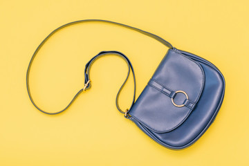 Beautiful women bag of blue leather on yellow background. The view from the top. Flat lay.