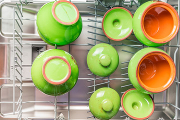 Four green ceramic pots lie in the lower compartment of the dishwasher
