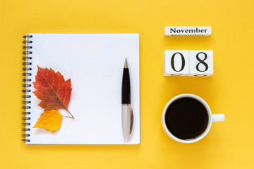 Autumn composition. Wooden calendar November 8 cup of coffee, empty open notepad with pen and yellow oak leaf on yellow background. Top view Flat lay Mockup Concept Hello November