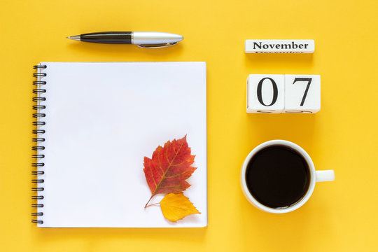 Autumn composition. Wooden calendar November 7 cup of coffee, empty open notepad with pen and yellow oak leaf on yellow background. Top view Flat lay Mockup Concept Hello November