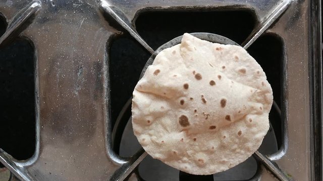  footage of making of Phulka a kind of Chapati: Indian thin bread made from wheat dough being baked on gas stove in home.