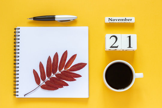 Autumn composition. Wooden calendar November 21 cup of coffee, empty open notepad with pen and yellow oak leaf on yellow background. Top view Flat lay Mockup Concept Hello November