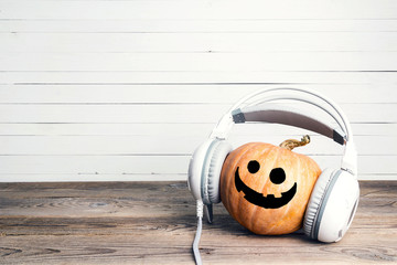 Halloween pumpkin with funny face in headphones. Copy space for text.