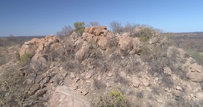 Establishing shot revealing African landscape behind rocky outcrop aerial