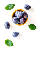 Blue plum for dessert. Purple plum and leaves pattern on white background top view copy space