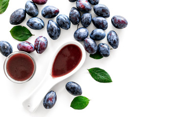 Fresh tkemali sauce. Traditional caucasian, georgian sauce or plum jam in spoon near plums on white background top view copy space