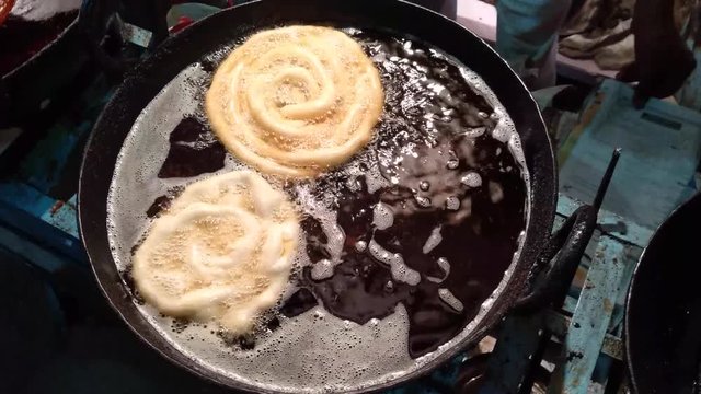 4K video of Indian sweet Jalebi being cooked in a road touching restaurant.Variety of cheap food at road side food stall is served fresh to customers in Indore, Madhya Pradesh, India.