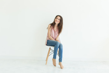 Beautiful brunette student woman sitting on a chair on white background with copy space