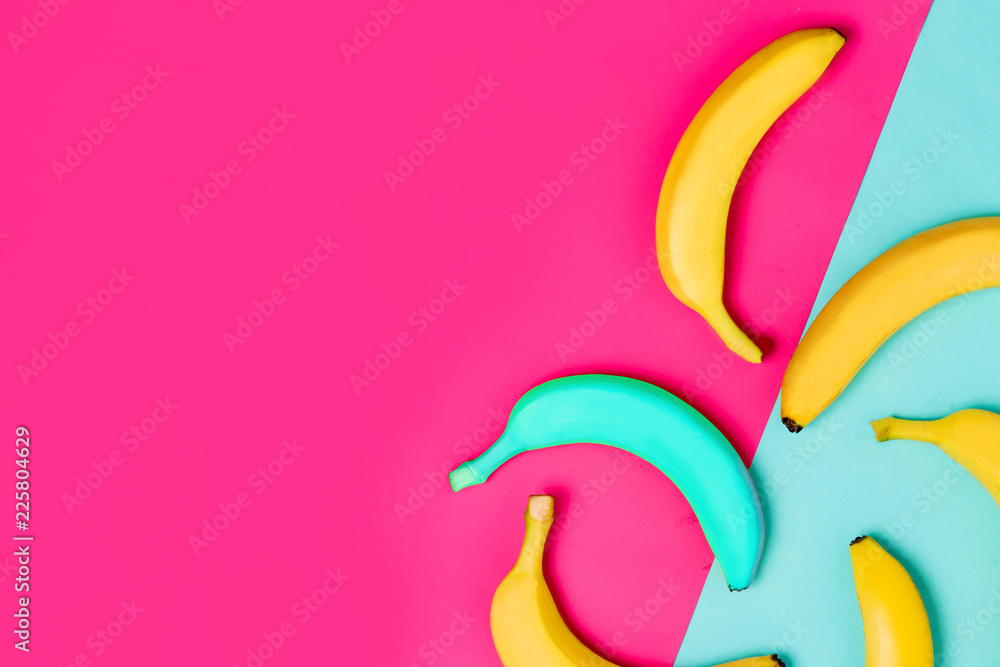 Poster flat lay of yellow and one blue banana on colorful background with copy space