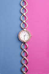 Fototapeta na wymiar women's gold wrist watch with diamonds on the color background