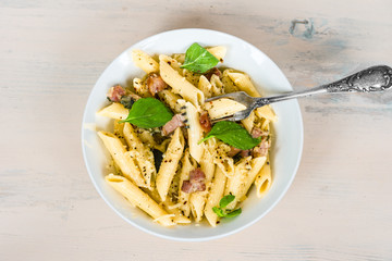Italian food - pasta with pancetta, parmesan cheese and basil on a plate close-up, top view.