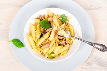 Italian food - pasta with pancetta, parmesan cheese and basil on a plate close-up, top view.