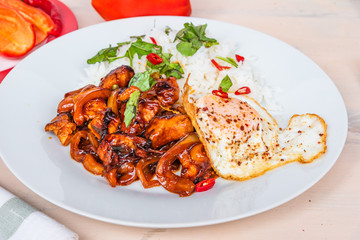 Thai food - chicken in spicy sauce with rice and fried egg close-up.