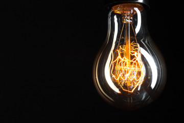 Fototapeta na wymiar A classic Edison light bulb on dark background with space for text