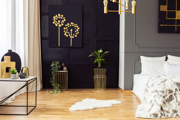 Dark grey bedroom interior with fur rug, gold accessories, simple painting and window with curtains...