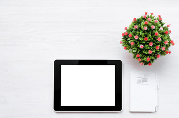 Laptop computer with blank screen, calendar notebook and green plant on the white office table background.