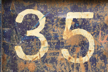 white number thirty-five on a rusty rough, peeling metal surface