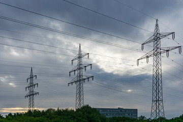 power transmission line pylons with threatening dark clouds background