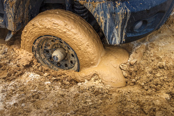 The wheel of the offroad car stuck in the wet sand ground