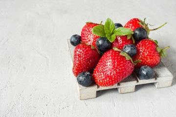 Fresh berries strawberries blueberries mint on a wooden stand, g