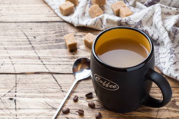 Cup of hot steaming black coffee with sugar cubes on wooden tabl