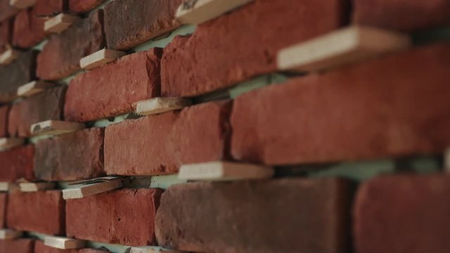 Close up of red brick construction sunlight block brick bricklayer building cement construction builder gloves hand layer mason trowel work worker hard job material industrial site yellow