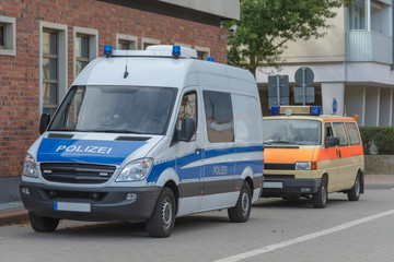 Einsatzwagen der Polizei und ein Krankenwagen parken am Rand einer Demo