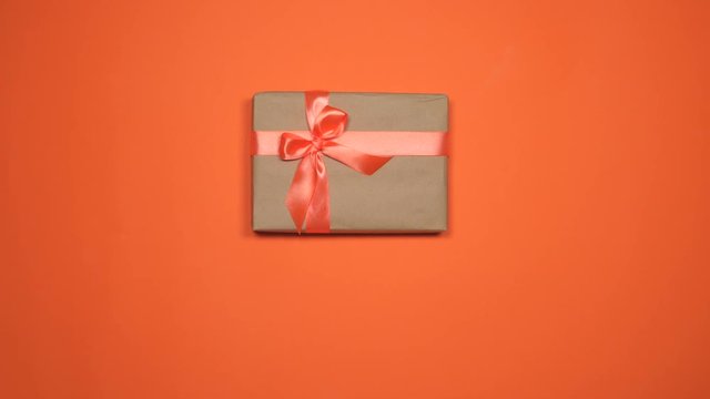 Woman hands putting gift boxes over orange flat lay