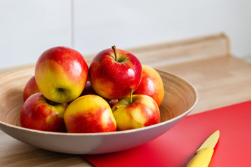 rot gelbe &auml;pfel in einer obstschale,mit einem roten schneidebrett und einem gelben messer