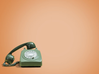 Vintage green rotary phone with headset removed on a retro orange background with space for copy...