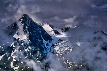 ośnieżone szczyty alpejskie w chmurach i mgłach - obrazy, fototapety, plakaty