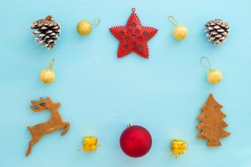 Christmas composition.  Frame made of gift boxes,  reindeer, balls, pine cones, red star and christmas tree on blue background. Creative flat lay, top view design