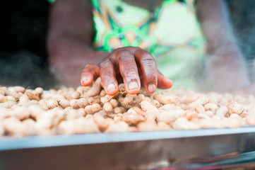 black hand of african woman touching delicious peanuts dish smoking after cooking