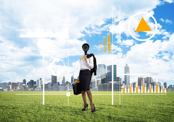 Camera headed woman standing on green grass against modern cityscape
