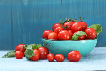 Red tomatoes in a bowl on blue background.