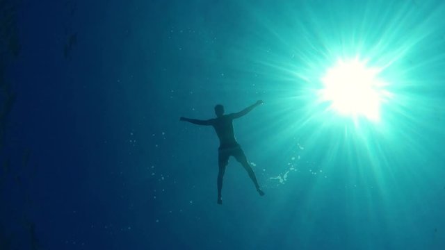 Man floating on water, bottom of the sea POV