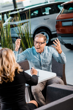 angry adult man shouting at female car dealer in salon
