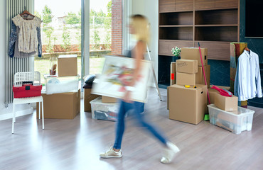 Young woman carrying painting in her new home